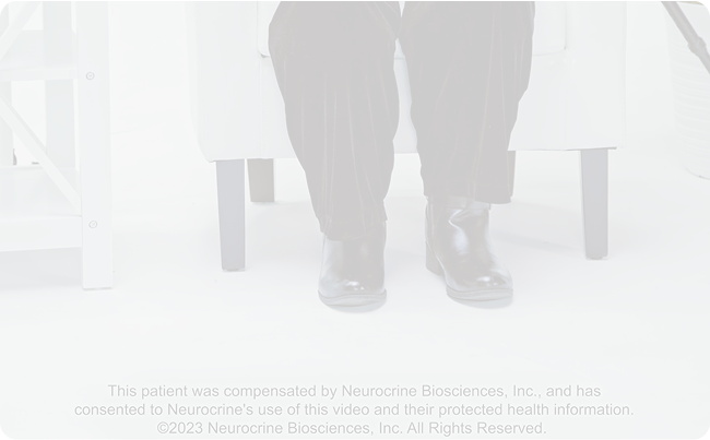 A patient sits across a doctor to be evaluated for symptoms using the Abnormal Involuntary Movement Scale (AIMS), Video Screenshot